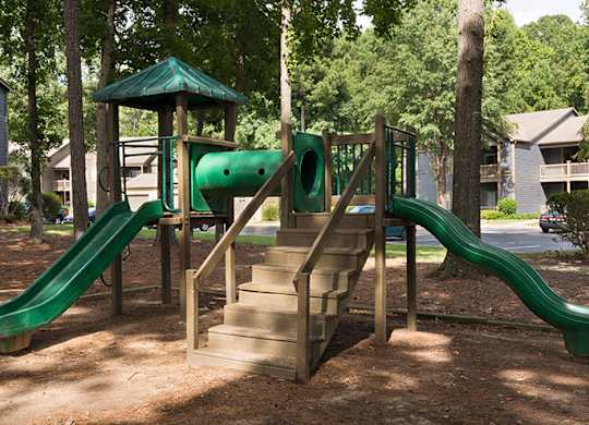A playground with a green slide and a wooden structure at Austin Chase Apartments, Georgia