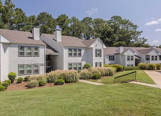 A large house with a grey roof and a green lawn in front.