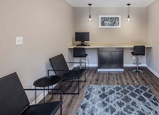 A room with a desk, chairs, and a rug.