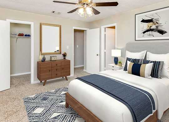 A bedroom with a large bed, a dresser, and a ceiling fan.