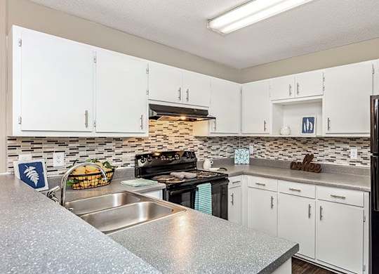 A kitchen with white cabinets and a black refrigerator.