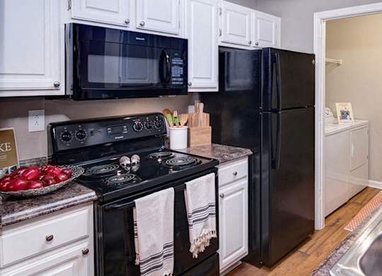 A kitchen with black appliances and white cabinets at Huntington Chase Apartments, Warner Robins, GA