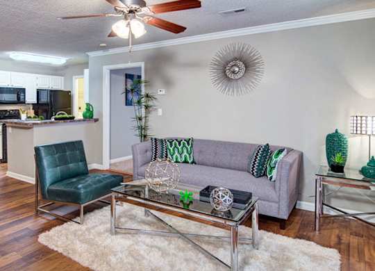 A living room with a grey couch and a glass coffee table at Huntington Chase Apartments, Warner Robins