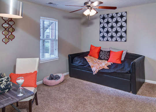 A living room with a black couch and a ceiling fan at Huntington Chase Apartments, Georgia