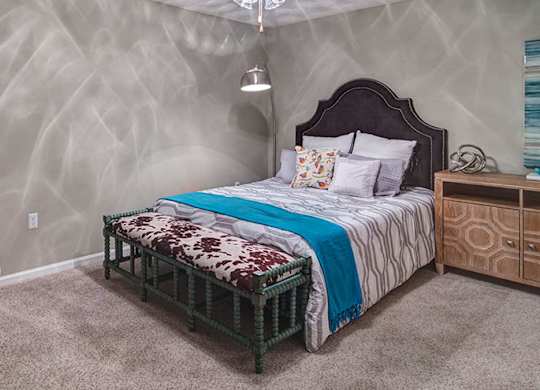 A bedroom with a bed, nightstand, and chair.