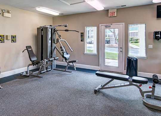 A gym with a variety of equipment including a squat rack, a leg press machine, and a bench press.