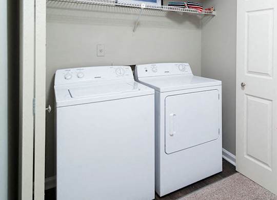 Two white washing machines in a small laundry room.