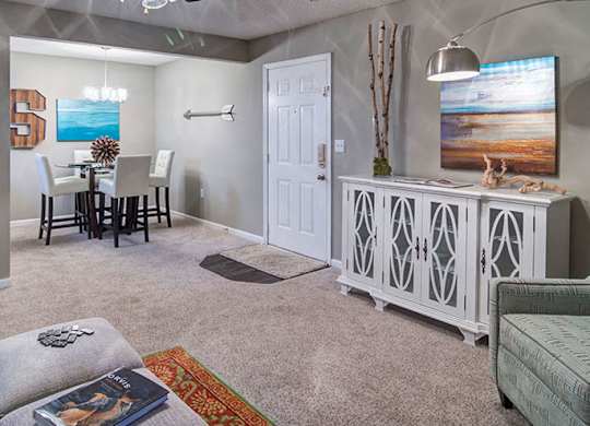 A living room with a grey couch, a white cabinet, and a painting on the wall.