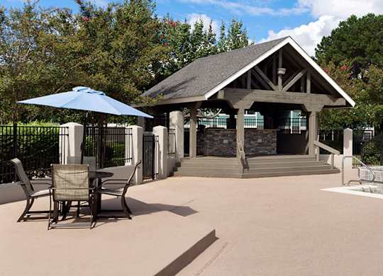 A poolside patio with a gazebo and chairs.