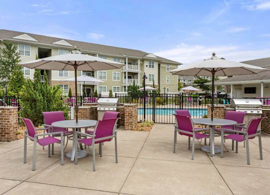 Outdoor grilling area with dining tables and umbrellas at Colony at Centerpointe Apartments, Midlothian, Virginia