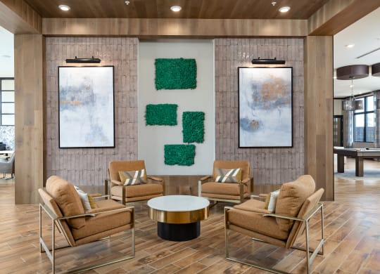 a lobby with a table and chairs and two paintings on the wall at The Flats at Southlawn Apartments, Lawrenceville