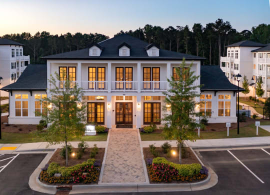 an image of a large house with lights on in a parking lot at The Quincy Apartments, Georgia, 30102