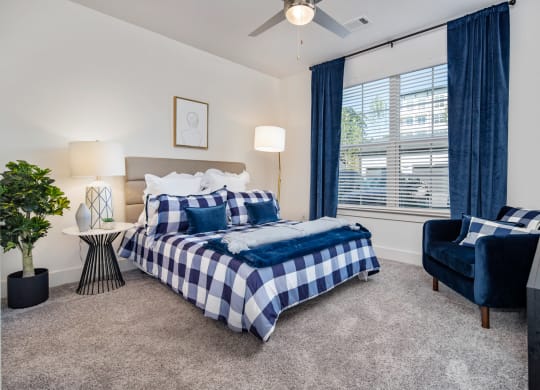 a bedroom with a bed and a chair and a ceiling fan at The Quincy Apartments, Acworth, Georgia