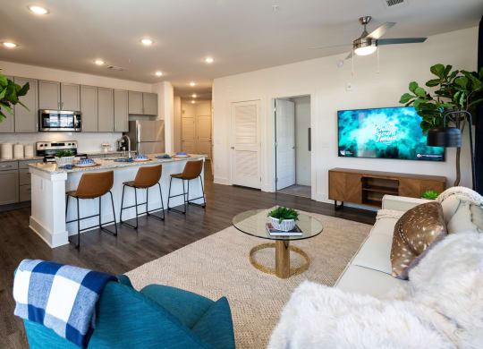 an open living room and kitchen with a large screen tv at The Quincy Apartments, Acworth, GA, 30102