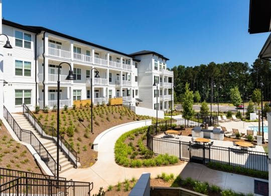 a view of the exterior of an apartment building with a courtyard and benches at The Quincy Apartments, Acworth, GA