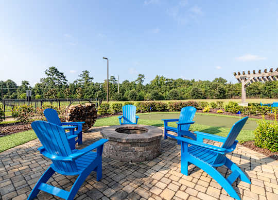 A fire pit surrounded by blue chairs in a garden.