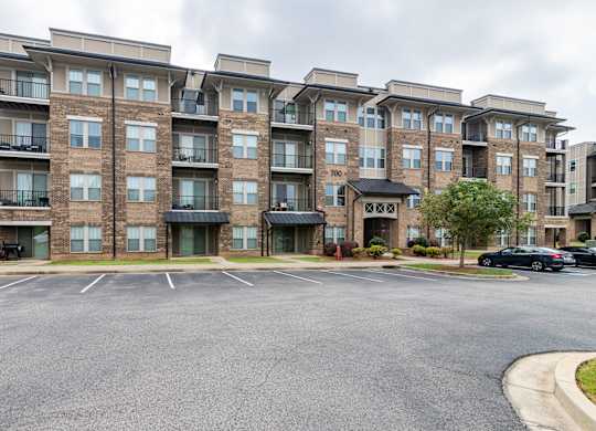 A large apartment complex with a parking lot in front.