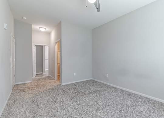 A room with a carpeted floor and a ceiling fan.