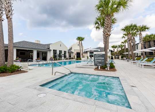 A pool surrounded by palm trees and lounge chairs.