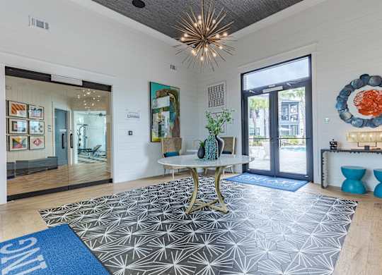 A spacious living room with a patterned rug, a gold chair, and a large window.