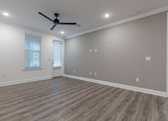 A room with a ceiling fan and wooden flooring.