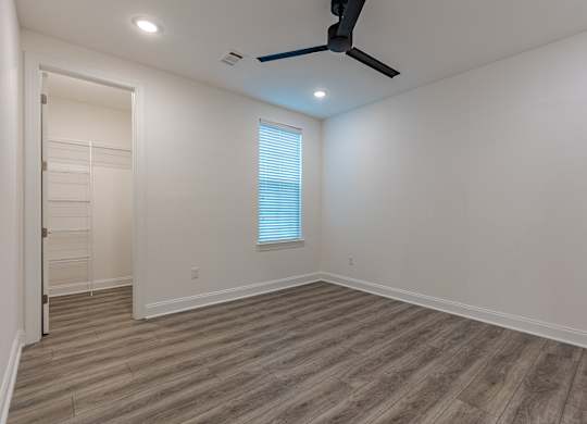 A room with a ceiling fan and a window with blinds.