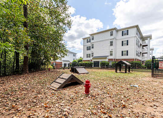 A red fire hydrant sits in a field of leaves in front of a white apartment building.