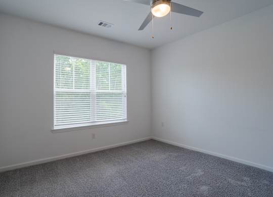 A room with a ceiling fan and a window with blinds.