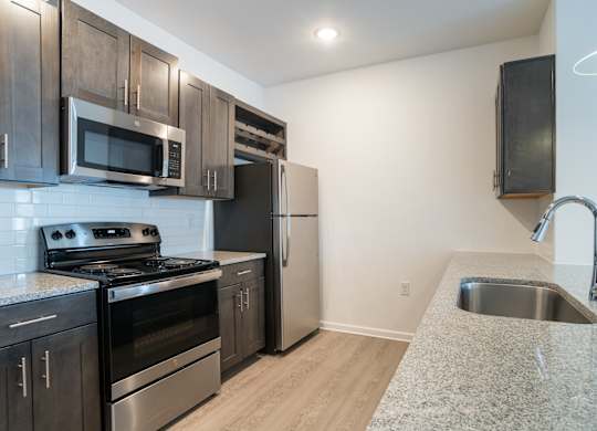 A kitchen with a stove, microwave, and refrigerator.