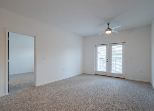 A room with a ceiling fan and carpeted floor.