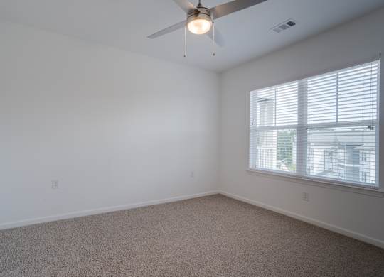 A room with a ceiling fan and a window with blinds.