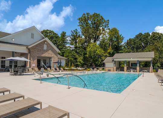 A large swimming pool with sun loungers and a building in the background.