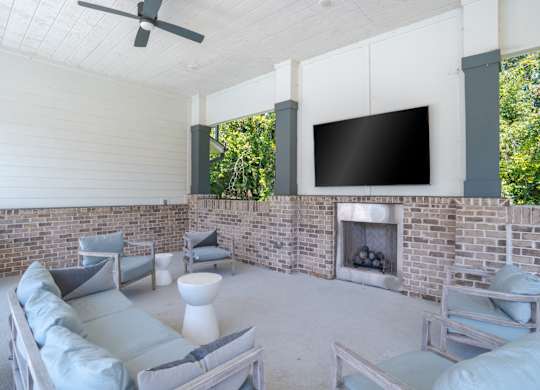 A modern living room with a brick fireplace and a flat screen TV mounted on the wall.
