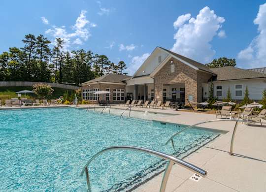 A large swimming pool in front of a building with a sunny sky.