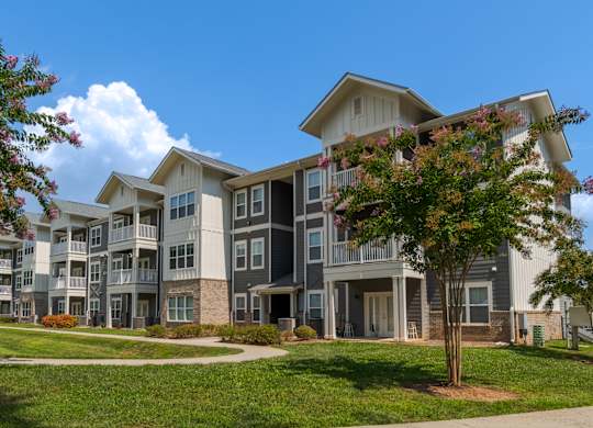 A large apartment complex with a tree in front of it.
