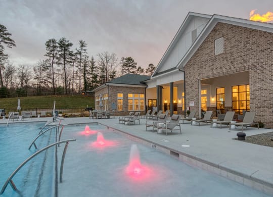the pool is lit up at dusk next to a brick building at Retreat at Arden Farms, Arden