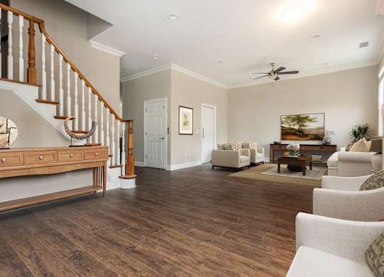 A living room with a staircase and a ceiling fan.