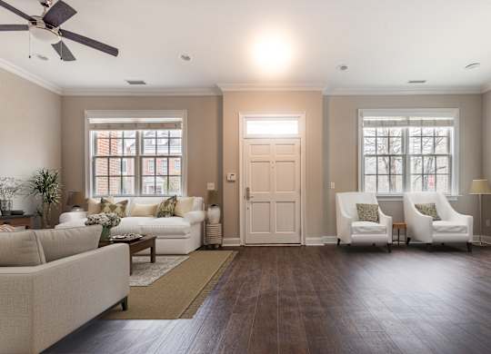 A living room with a white couch, two chairs, and a ceiling fan.