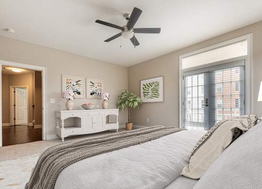 A bedroom with a large bed and a ceiling fan.