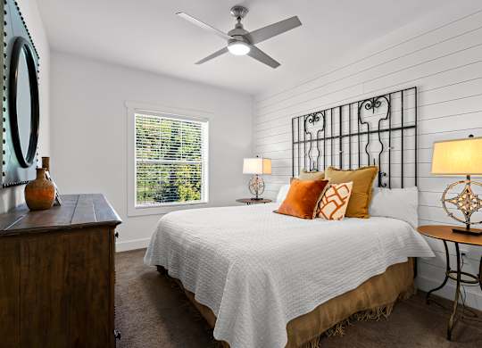 A bedroom with a bed, a dresser, and a ceiling fan.