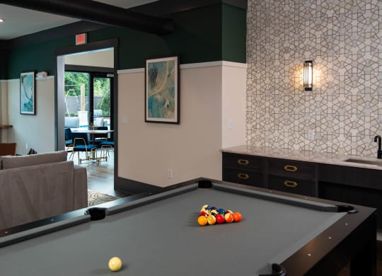 a pool table in a living room with a bar  at One Riverside Apartments, Chattanooga, TN, 37403