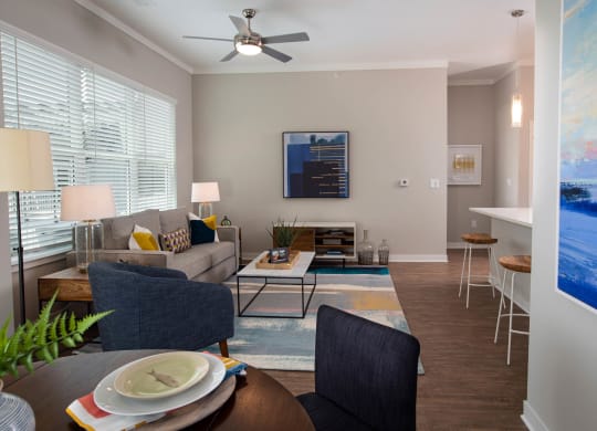 a living room with a couch and a table and a ceiling fan at One Riverside Apartments, Chattanooga