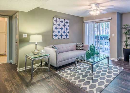 A living room with a glass coffee table and a grey sofa. at The Colony at South Park, Aiken, SC