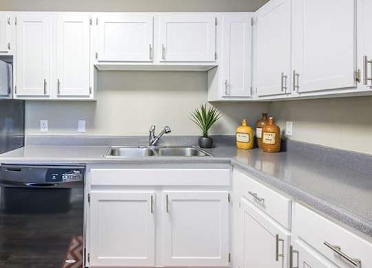 A kitchen with white cabinets and a black fridge. at Woodwinds, South Carolina