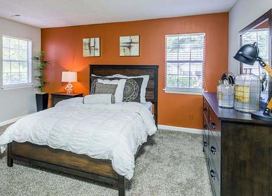 A bedroom with a bed, nightstand, and a window. at Woodwinds, Aiken, SC, 29803