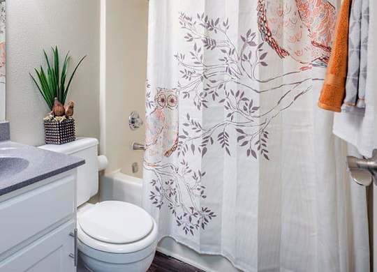 A bathroom with a toilet, sink, and shower curtain. at Woodwinds, Aiken, SC, 29803