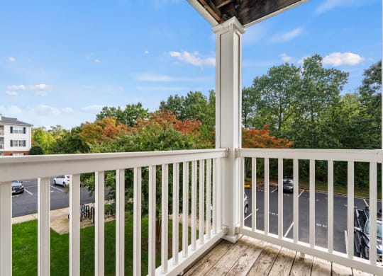 a balcony with a view of a parking lot and trees at SomerHill Farms Apartments, Gainesville, VA