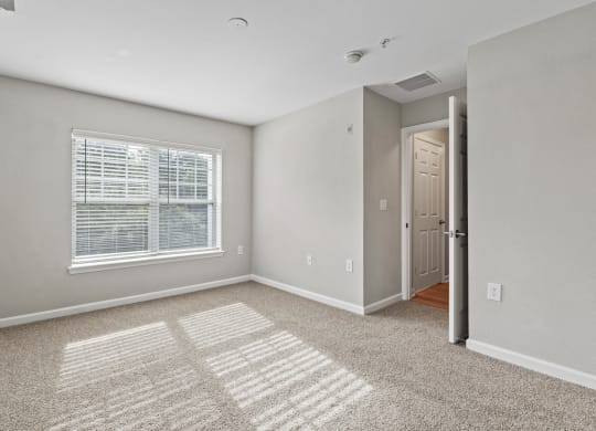 an empty bedroom with a large window and carpet at SomerHill Farms Apartments, Gainesville, VA 20155