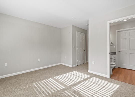 the living room of an apartment with a rug and a door to the bathroom at SomerHill Farms Apartments, Gainesville, 20155