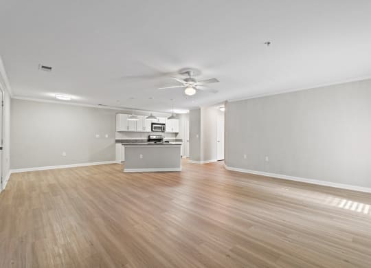 the living room and kitchen of an empty house with wood floors and a ceiling fan at SomerHill Farms Apartments, Virginia , 20155